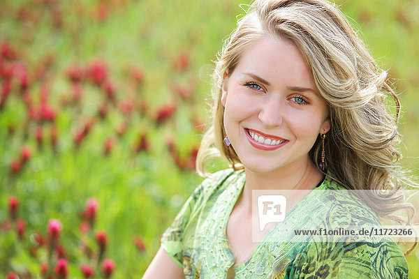 Porträt einer jungen Frau mit blondem lockigem Haar in einem Blumenfeld; Oregon  Vereinigte Staaten von Amerika'.