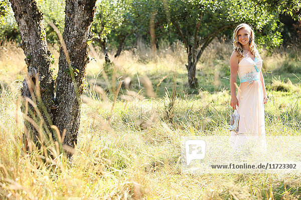 'A young woman with blond hair and a flowing dress stands in a field with tall grass; Oregon  United States of America'