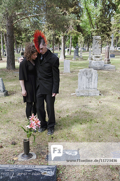 Ein junger Mann und eine junge Frau legen Blumen neben einen Grabstein; Edmonton  Alberta  Kanada .