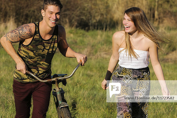 'A young man and young woman walk together as the young man pushes a bicycle; Oregon  United States of America'