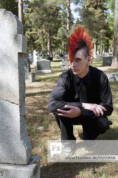 Ein junger Mann trauert an einem Grabstein auf einem Friedhof; Edmonton  Alberta  Kanada