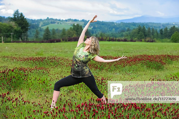 Eine Frau macht Yoga in einem Feld mit Wildblumen und Bergen im Hintergrund; Oregon  Vereinigte Staaten von Amerika'.