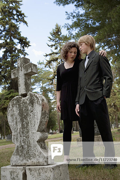 Ein Bruder und eine Schwester trösten sich gegenseitig an einem Grab auf einem Friedhof; Edmonton  Alberta  Kanada'.