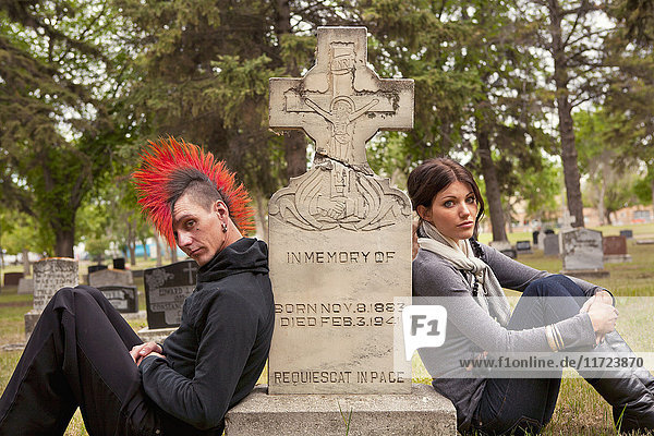 Ein junger Mann und eine junge Frau sitzen an einem Grabstein auf einem Friedhof; Edmonton  Alberta  Kanada