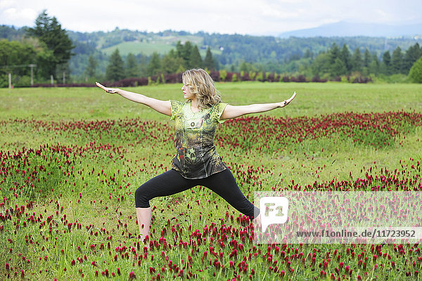 Eine Frau macht Yoga in einem Feld mit Wildblumen und Bergen im Hintergrund; Oregon  Vereinigte Staaten von Amerika'.