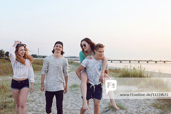 Junge Männer  junge Frau und Teenager-Mädchen (16-17) gehen am Strand spazieren