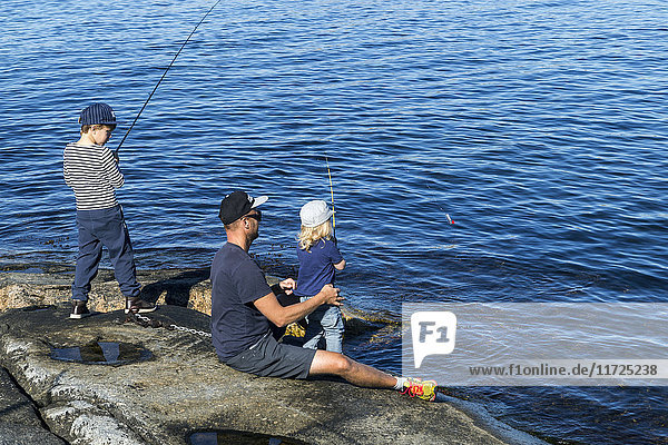 Vater mit Söhnen beim Fischen auf See