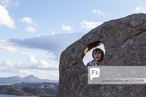 Junge auf Felsen schaut in die Kamera