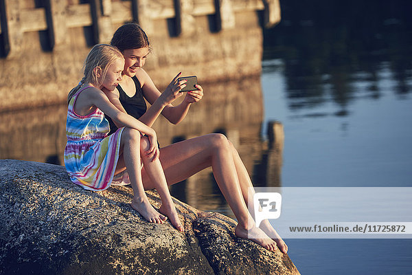 Girls using cell phone by lake