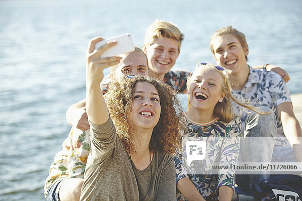 Glückliche Freunde machen ein Selfie am Wasser