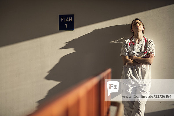 Female doctor standing by wall