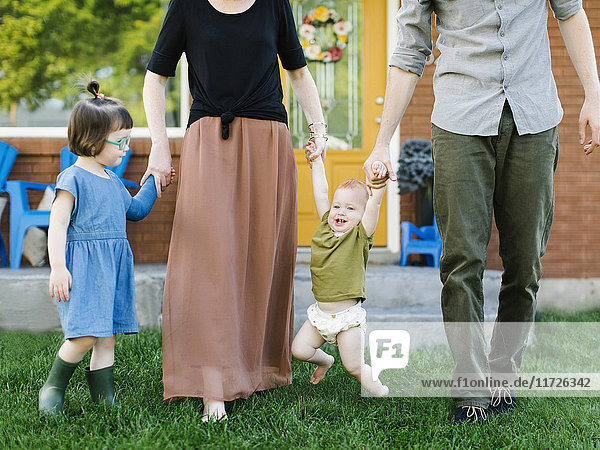 Parents with daughters (2-3  12-17 months) standing on grass
