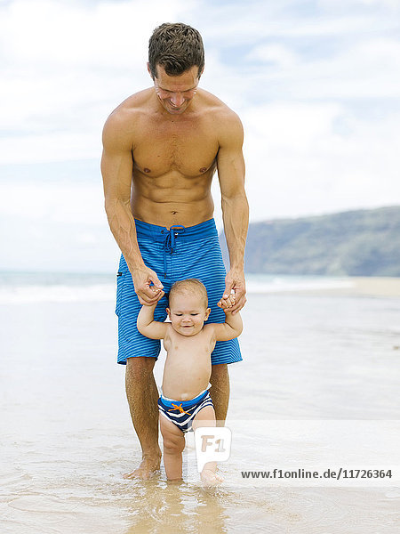 Sohn (12-17 Monate) lernt mit Vater am Strand laufen