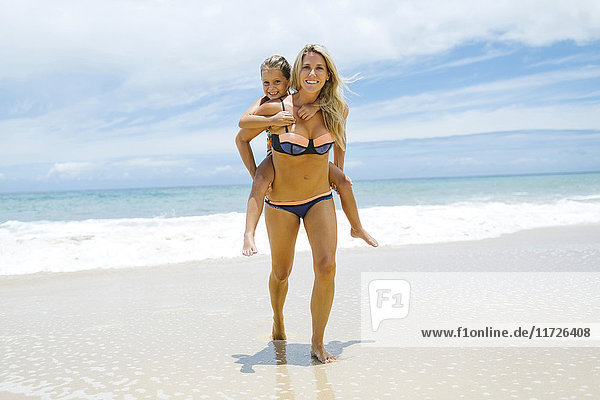 Tochter (6-7) spielt mit Mutter am Strand an einem sonnigen Tag