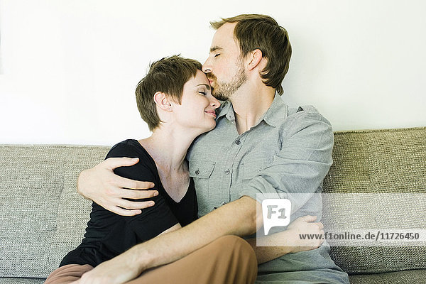 Couple embracing and kissing on sofa