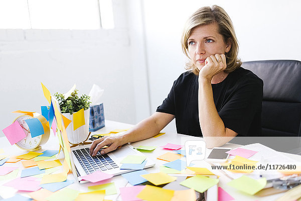Mature woman at office overwhelmed by adhesive notes