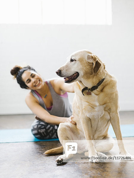 Frau übt Yoga mit Hund