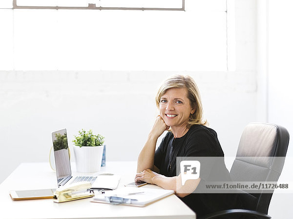 Porträt einer reifen Frau im Büro mit Hand am Kinn