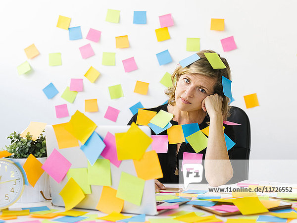Portrait of Mature woman at office covered with adhesive notes