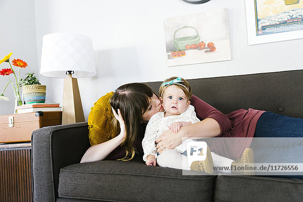 Mother and daughter (12-17 months) on sofa