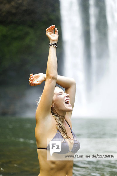 USA  Hawaii  Kauai  Frau watet in einem Teich neben einem Wasserfall