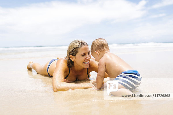 Mother playing with son (12-17 months) on beach