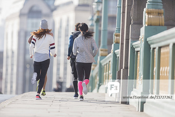 Läuferinnen und Läufer auf dem sonnigen Bürgersteig der Stadt