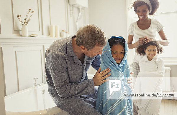 Multiethnische Eltern trocknen Töchter mit Handtüchern nach dem Baden im Bad.