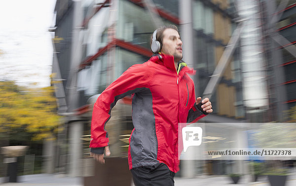 Mann läuft mit Kopfhörern an einem städtischen Gebäude vorbei.