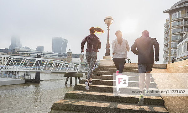 Läuferinnen und Läufer  die die sonnige  städtische Uferpromenade hinauflaufen.