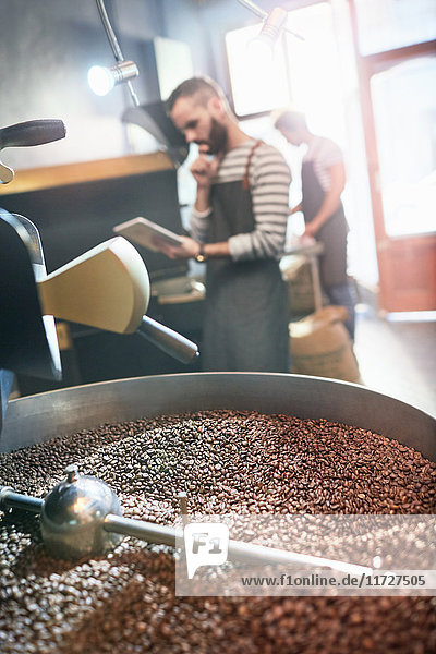Kaffeeröster mit digitaler Tablette hinter dem Rösten von Kaffeebohnen