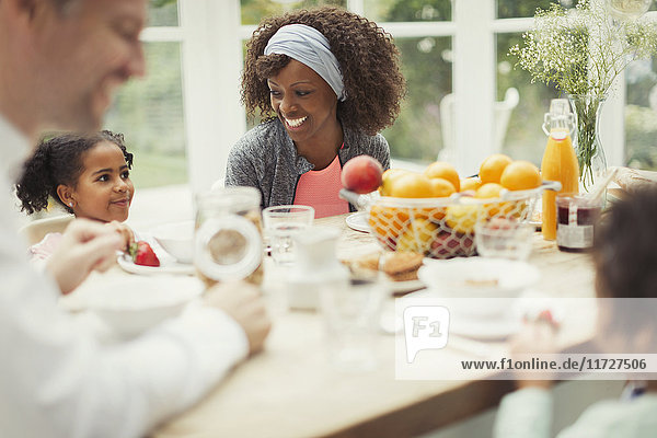 Multi-ethnic young family eating breakfast at table