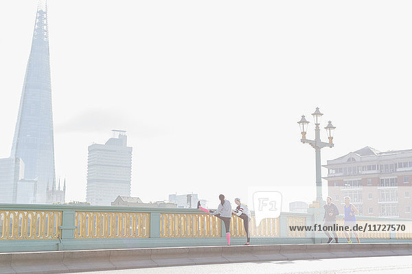 Läufer beim Laufen und Strecken auf der sonnigen  nebligen Stadtbrücke  London  UK