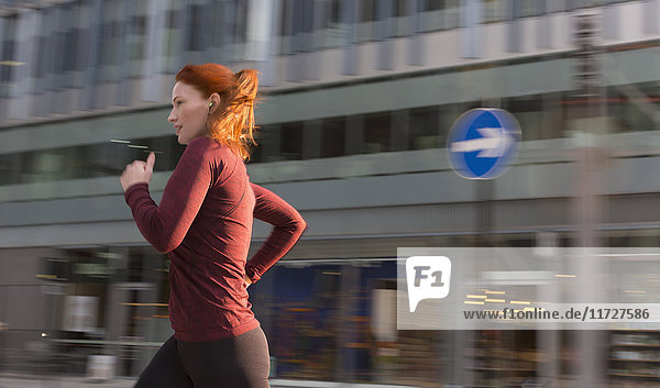 Läuferin  die an einem städtischen Gebäude entlang läuft.