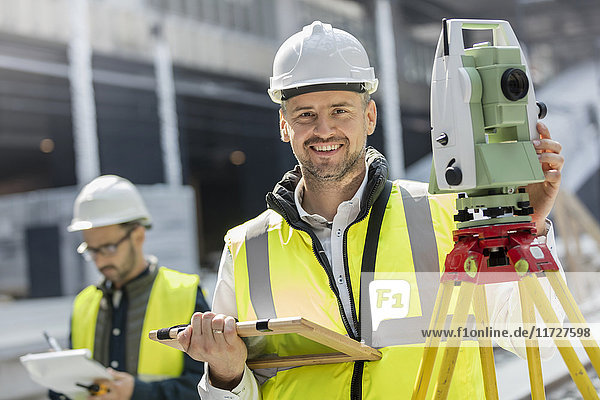 Portrait lächelnder Ingenieur mit Theodolit auf der Baustelle