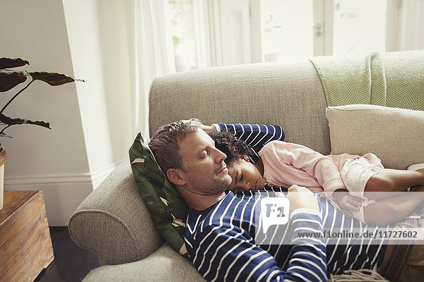 Affectionate  serene multi-ethnic father and daughter napping on sofa