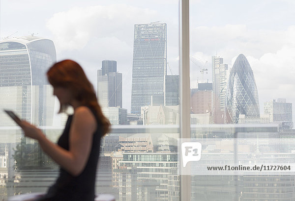Geschäftsfrau mit digitalem Tablett am Stadtfenster mit Stadtansicht  London  UK