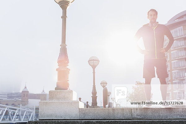 Portrait selbstbewusster männlicher Läufer am sonnigen Laternenpfahl der Stadt