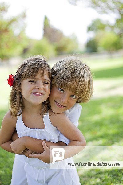 Cute boy hugging his sister in the park