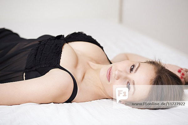 Porträt einer sinnlichen und nachdenklichen jungen Frau im Bett liegend