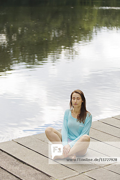 Woman relaxing on pier by a lake