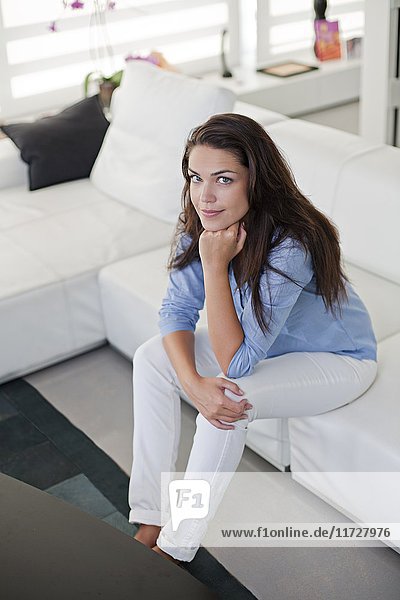 Portrait of a pretty brunette woman sitting on the sofa looking at camera