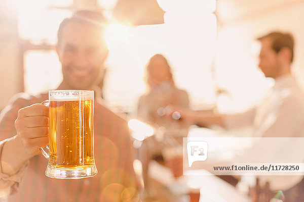 Porträt eines lächelnden Mannes mit Bierkrug in einer hell erleuchteten Bar