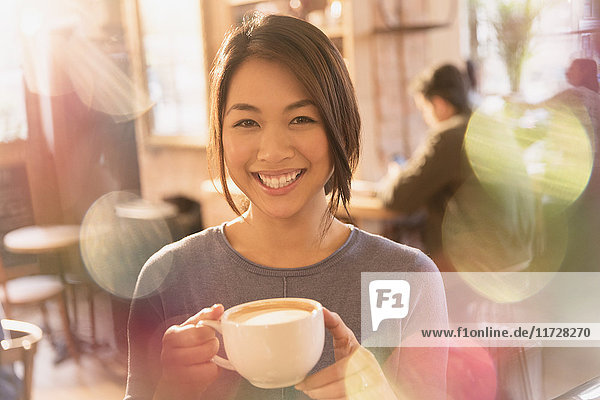 Porträt lächelnde Frau trinkt Cappuccino im Café