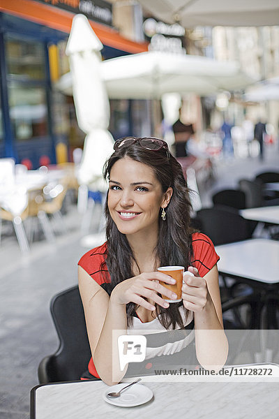 Porträt einer Frau bei einem Kaffee im Freien lächelnd vor der Kamera