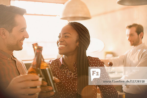 Smiling couple toasting beer bottles in bar