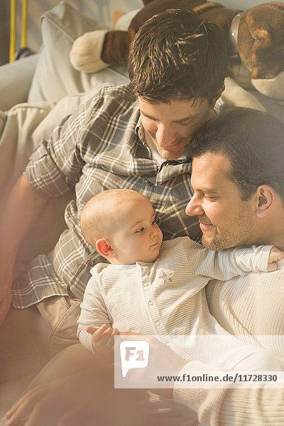 Affectionate male gay parents and son cuddling
