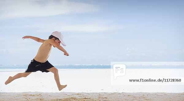 Playful boy running on tropical beach
