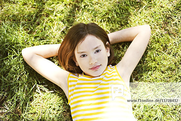 Young girl lying in the park looking at camera