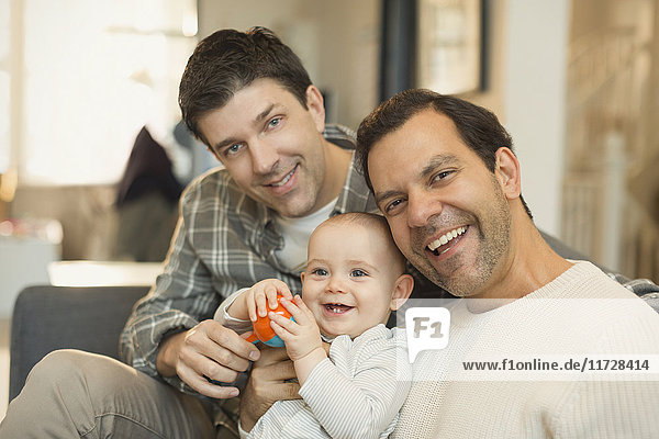 Portrait male gay parents holding cute baby son